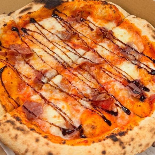 Captain’s Pizza Company's pizza with prosciutto, mozzarella, and balsamic glaze, in a pizza box.